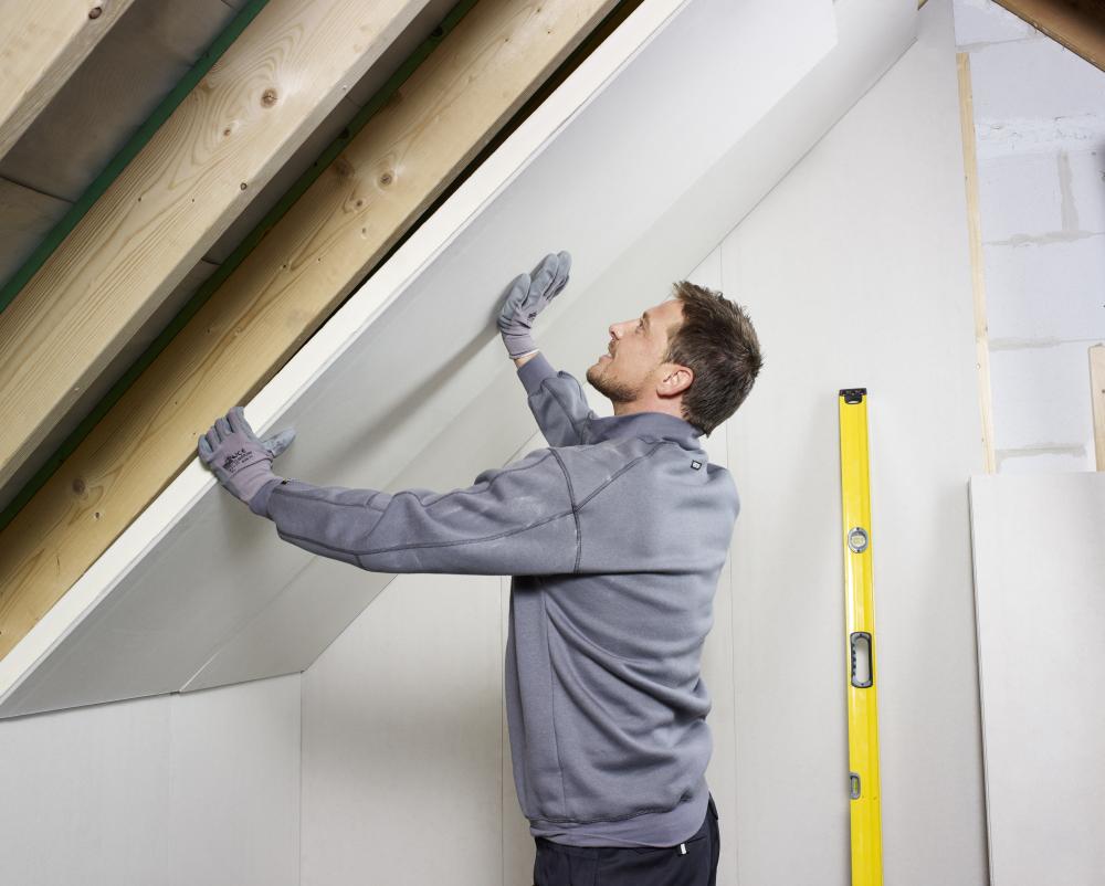 Tradesman installing plasterboard sheets onto a wall